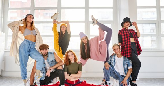 Junge Männer und Frauen posieren in Hip Hop Kleidung vor einer Fensterwand