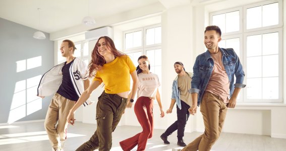 Junge Männer und Frauen tanzen in Formation in einem hellen Raum