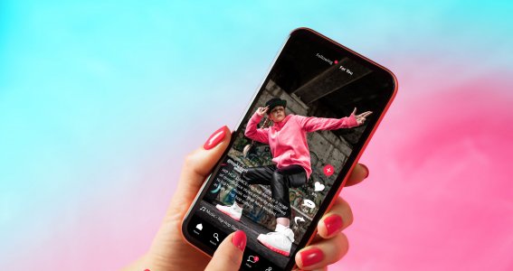 Eine Frauenhand spielt am Handy ein Tik Tok Video eines tanzenden Mädchens ab
