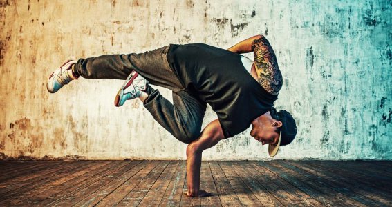 Ein Mann in dunkler Kleidung posiert in Breakdance Position