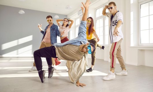 Ein junger Mann tanzt in der Mitte einer Gruppe Breakdance