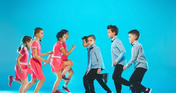 Mädchen in pinken Kleidern und Jungs in blauen Hemden stehen sich gegenüber und tanzen vor blauem Hintergrund