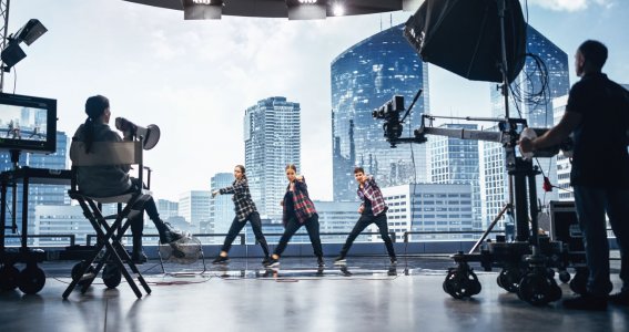 Drei Jugendliche tanzen vor einem Filmset und Hintergrund mit Hochhäusern