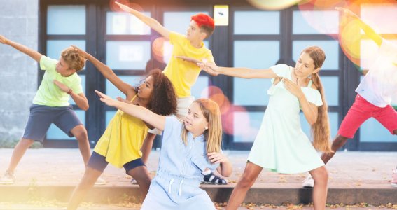 Eine Tanzgruppe von Kindern posiert auf Stufen vor einem Gebäude