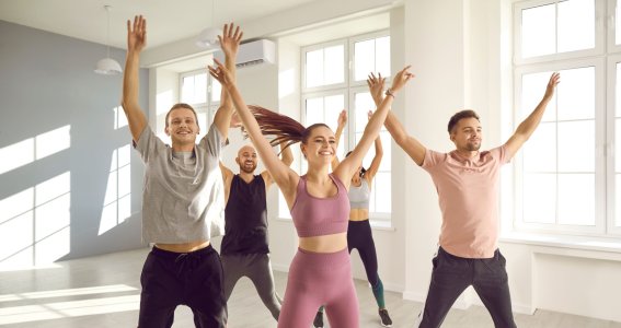 Eine fröhliche Gruppe in einem hellen Raum springt in Sportkleidung in die Höhe