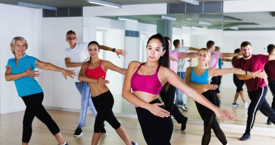Eine Tanzgruppe in sportlicher Kleidung im Tanzstudio vor einer Spiegelwand