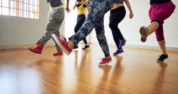 Eine Gruppe junger Tänzerinnen springt synchron mit einem Fuß nach vorne