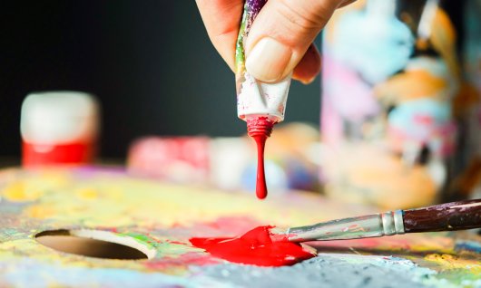 Rote Farbe tropft auf ein buntes Gemälde