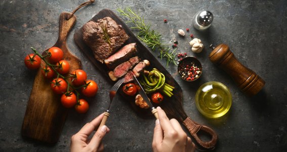 Fleisch wird auf Holzbrett geschnitten