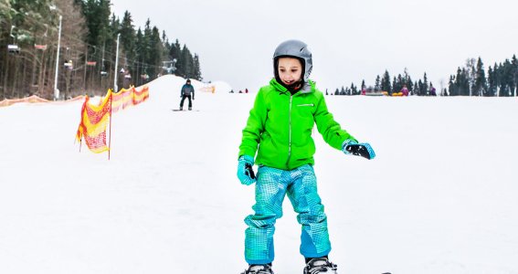 Mädchen lernt auf der Piste Snowboardfahren