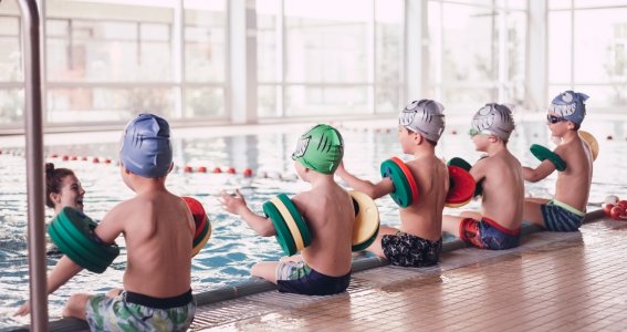 Jungs sitzen am Beckenrand mit Schwimmscheiben