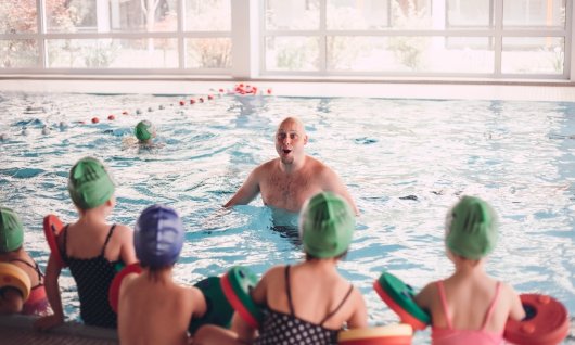 Schwimmlehrer wartet auf die Kinder im Wasser