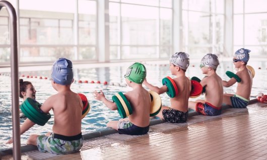 Kinder nehmen am Schwimmkurs teil.