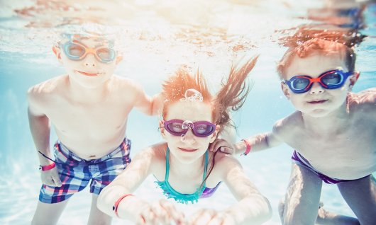 Drei Kinder tauchen mit Schwmmbrille