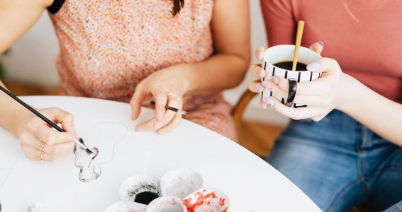 Zwei Frauen sitzen am Tisch eine malt die andere hat Tasse