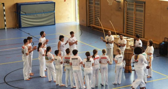 Eine Gruppe Kinder steht in einem Turnsaal vor Trainern mit Musikinstrumenten