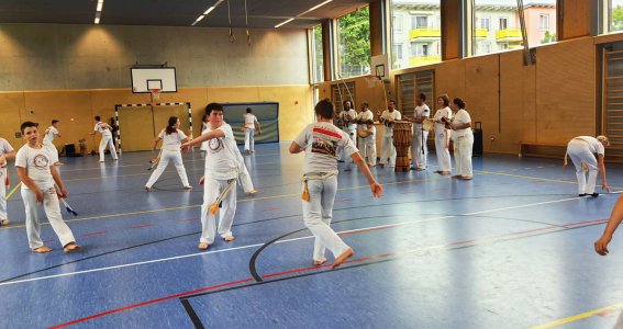 Kinder trainieren in einem Turnsaal Capoeira in weißer Sportbekleidung