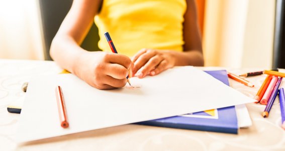 Kind zeichnet auf einem Blatt Papier