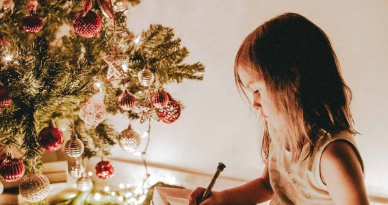 Mädchen malt etwas vor dem Weihnachtsbaum