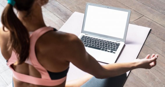 Frau macht Yoga vor dem Laptop