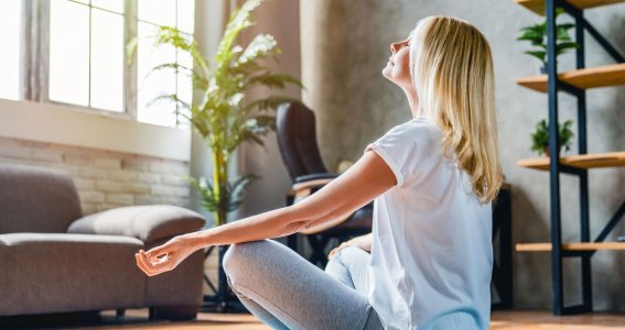 Eine Frau sitzt im Schneidersitz auf einer Yogamatte und meditiert