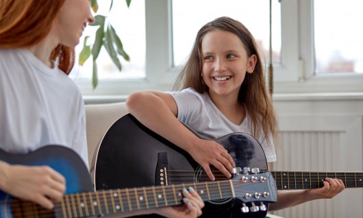 Mädchen lernt Gitarre spielen