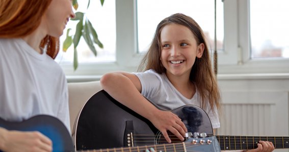 Mädchen lernt Gitarre spielen