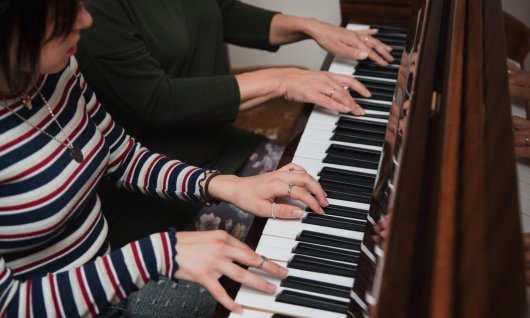 Zwei Personen drücken auf Klaviertasten