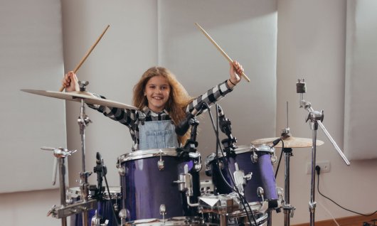 Mädchen sitzt am Schlagzeug