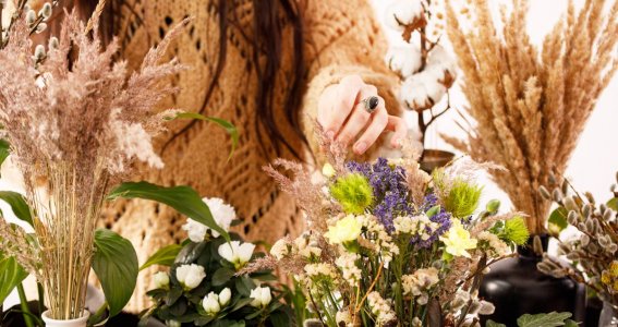 Eine Frau wählt aus unterschiedlichen Trockenblumen aus