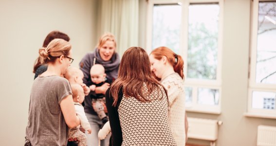 Mamas stehen im Kreis und halten ihre Babys