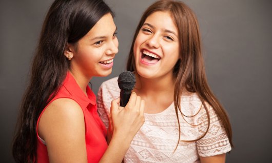 Zwei jugendliche Mädchen singen gemeinsam.