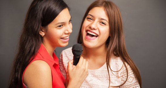 Zwei jugendliche Mädchen singen gemeinsam.