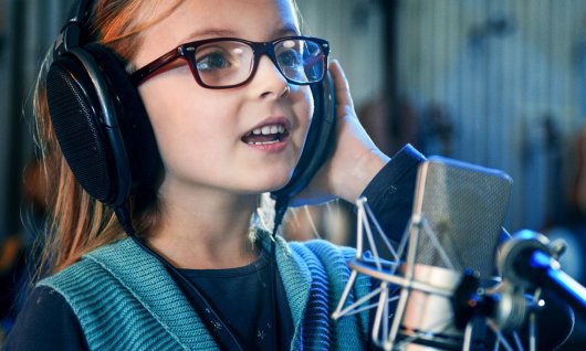 Kind singt mit Kopfhörern und Mikrophon