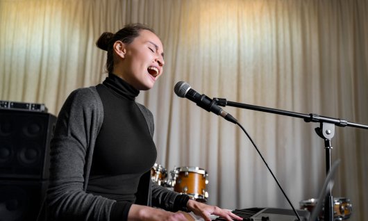 Frau singt und spielt auf einen Keyboard