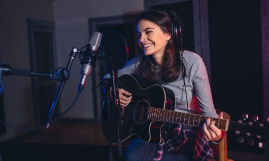 Frau sitzt lachend vor einem Mikrofon