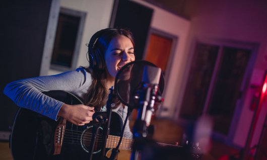 Jugendliche singt und spielt Gitarre 