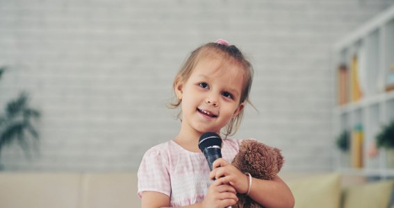 Mädchen hält Teddybär und Mikrofon