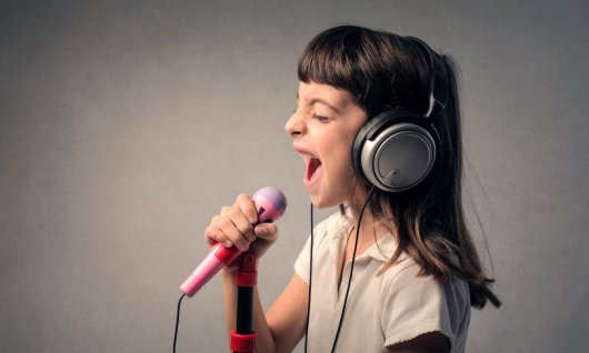 Gesangsunterricht für Kinder Kind trägt Kopfhörer und singt in ein Mikrofon