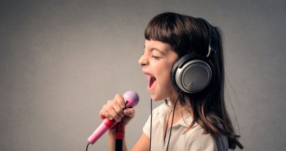 Kind trägt Kopfhörer und singt in ein Mikrofon