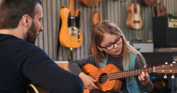 Mädchen mit Brille spielt Gitarre