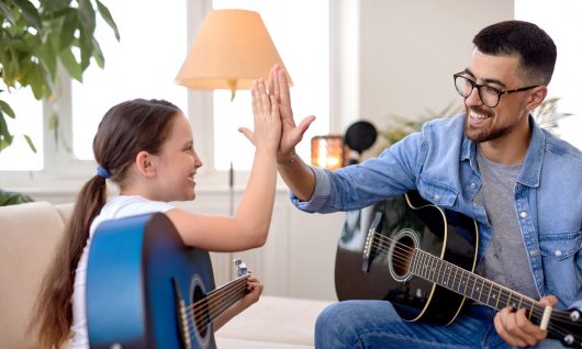 Gitarre lernen für Kinder Mädchen klatscht mit einem Mann ab