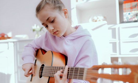 Gitarrenunterricht für Kinder in München Mädchen schaut auf eine Gitarre
