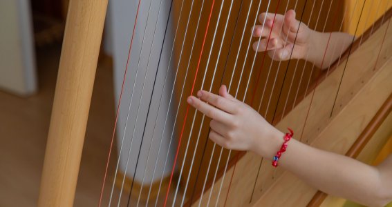 Kinderhände auf den Saiten einer Harfe