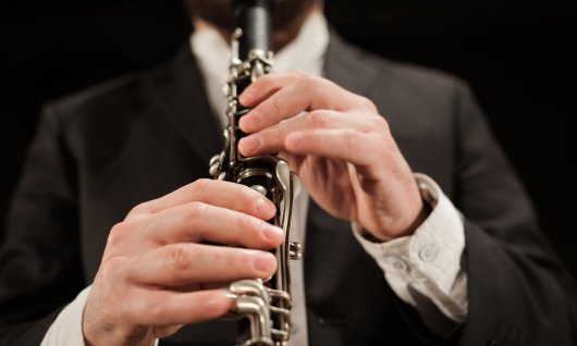 Mann im Anzug hält eine Klarinette