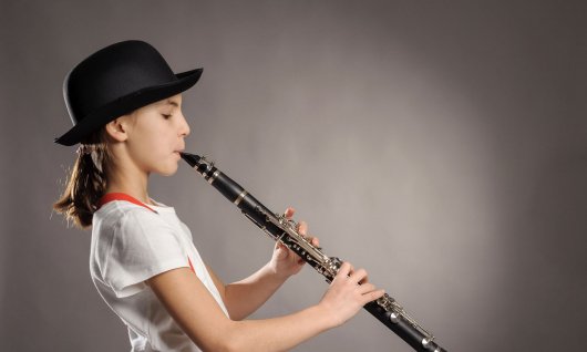 Klarinettenunterricht für Kinder Mädchen mit Hut spielt Klarinette