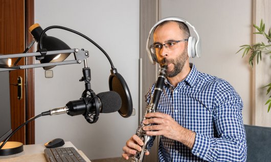 Online Klarinettenunterricht für Erwachsene Mann trägt Kopfhörer und spielt Klarinette in ein Mikro