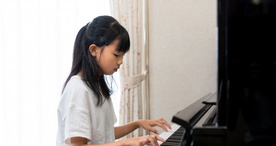 Mädchen drückt auf die Tastatur eines Klavieres
