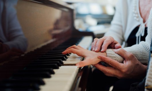 Unterricht im Klavier spielen für Kinder Kinderhände werden an Tastatur geführt