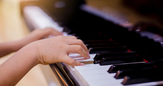 Kinderhände drücken auf Klaviertasten